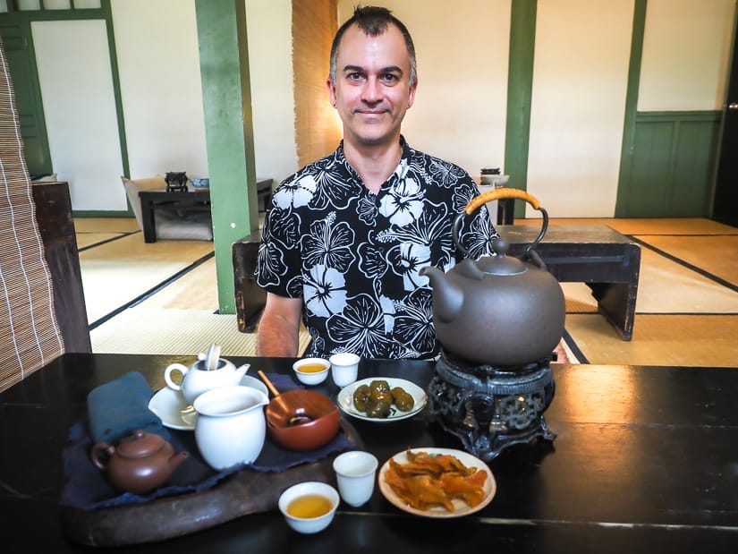 Nick Kembel seated at a low table in a traditional Taiwanese tea shop with various tea equipment on the table in front of him