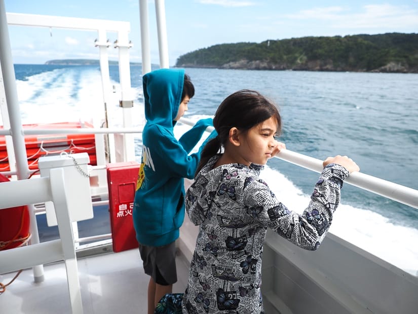 Two kids looking out from the side of a ferry towards Tashirojima island