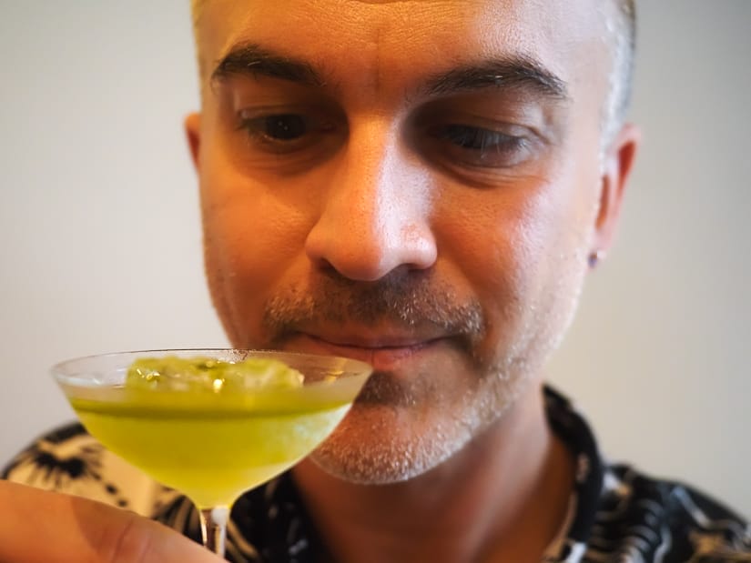 Close up of Nick Kembel's face as he looks down at a small, green tea cocktail in his hand