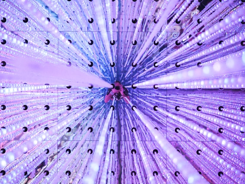 An artistic photo looking up at a ceiling through numerous hanging pieces of glass, with the reflection of the photographer (Nick Kembel) in the middle as he takes the photo upwards