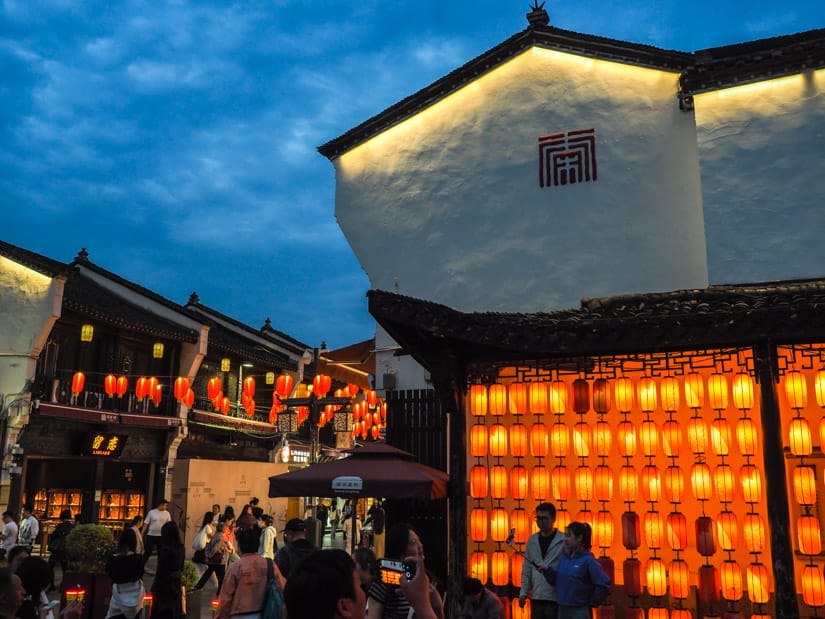 Entrance to Qinghefang pedestrian street at dusk, with wall of red lanterns on the right and more of them hanging over the street 