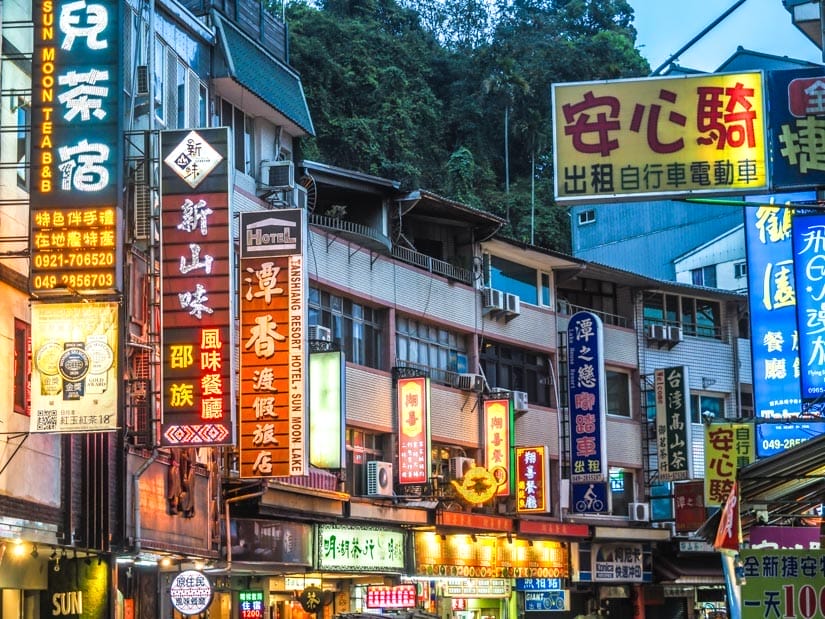 A row of connected restaurants along the main road in Shuishe village at Sun Moon Lake, shot in the evening, with lit up signs