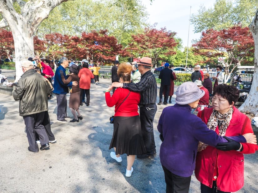 Several elderly Chinese couples doing ballroom dancing in a park