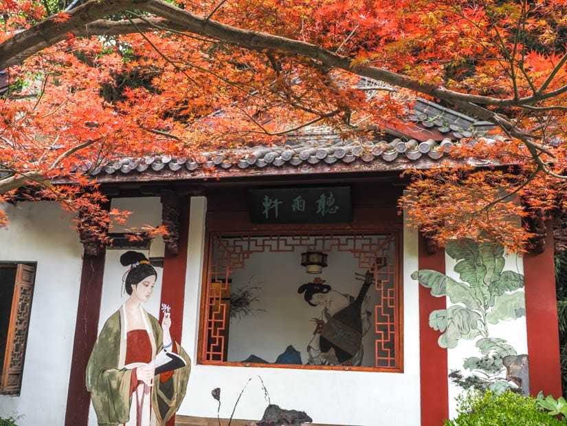 A red and white shrine in Laolongjing with paintings of women and red maple tree leaves above