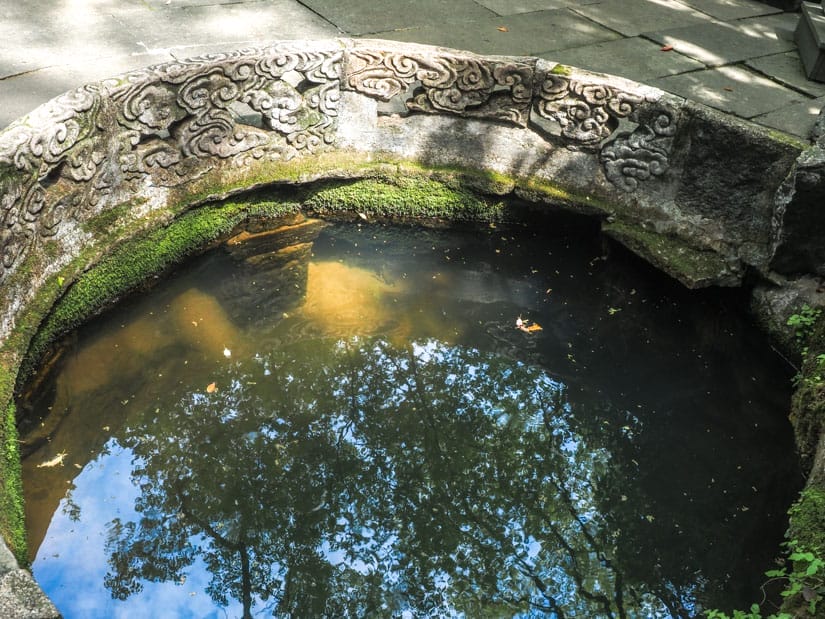 Looking down at a spring with short, round rock wall around it