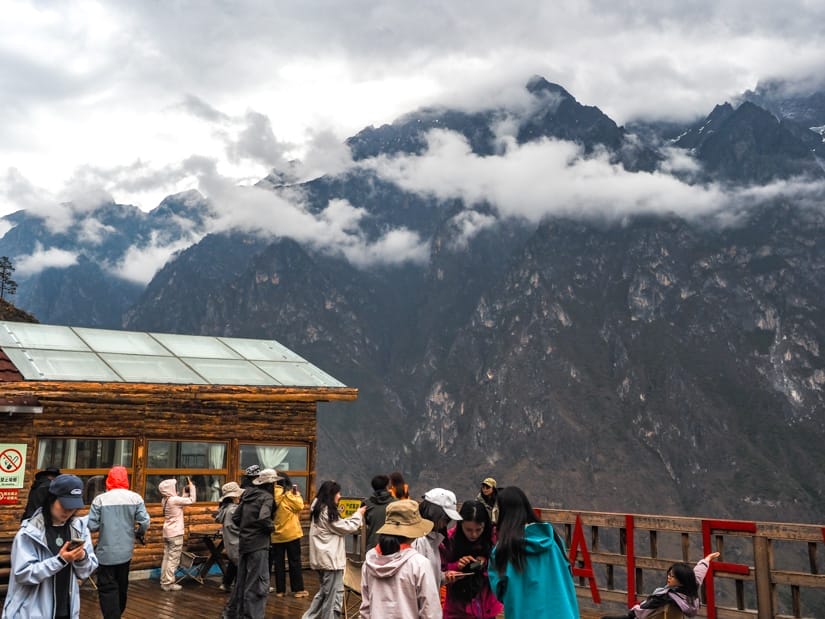 Groups of Chinese trekkers on a lookout platform with view of Tiger Leaping Gorge