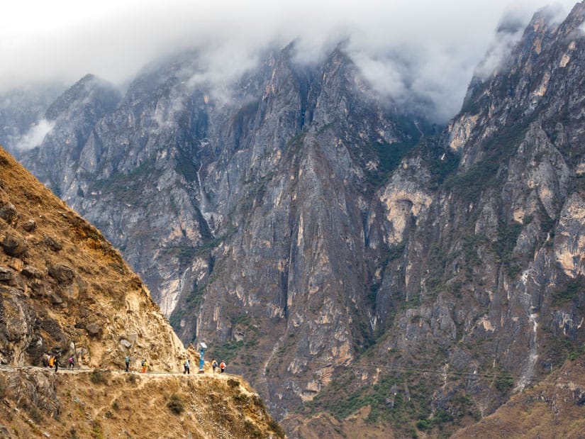 Some hikers rounding a corner in Tiger Leaping Gorge with dramatic scenery all around them