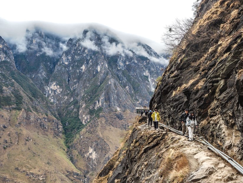 A couple trekkers following a narrow trail into a small valley