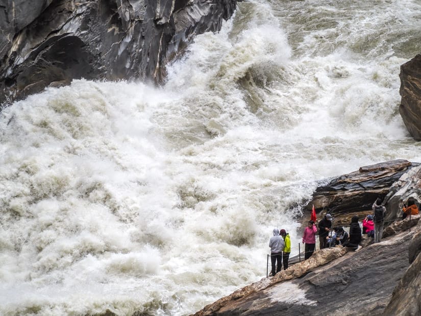 Close-up of huge rapids in a narrow section of the river with people watching it on the side