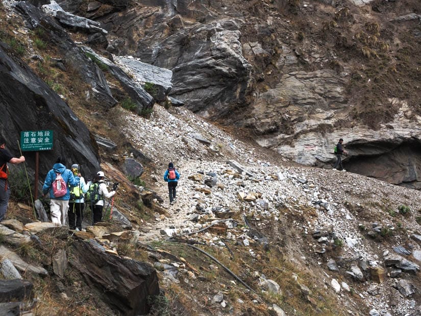 Some trekkers crossing a small landslide section of trail