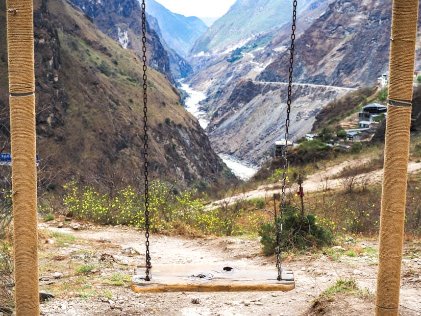 A simple wooden swing with view looking down Tiger Leaping Gorge behind it