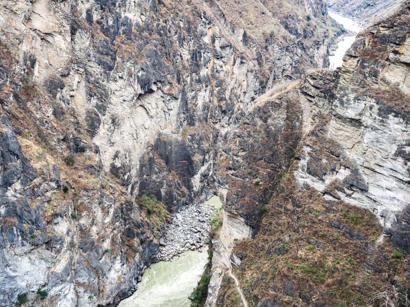 Looking down some steep cliffs at a very narrow section of Tiger Leaping Gorge