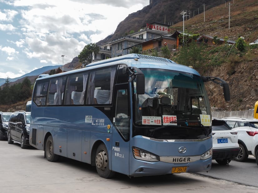 A blue bus packed in a lot in Tiger Leaping Gorge