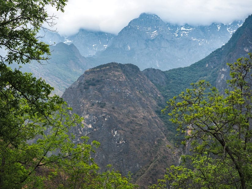Two layers of tall mountains with cloudy sky above