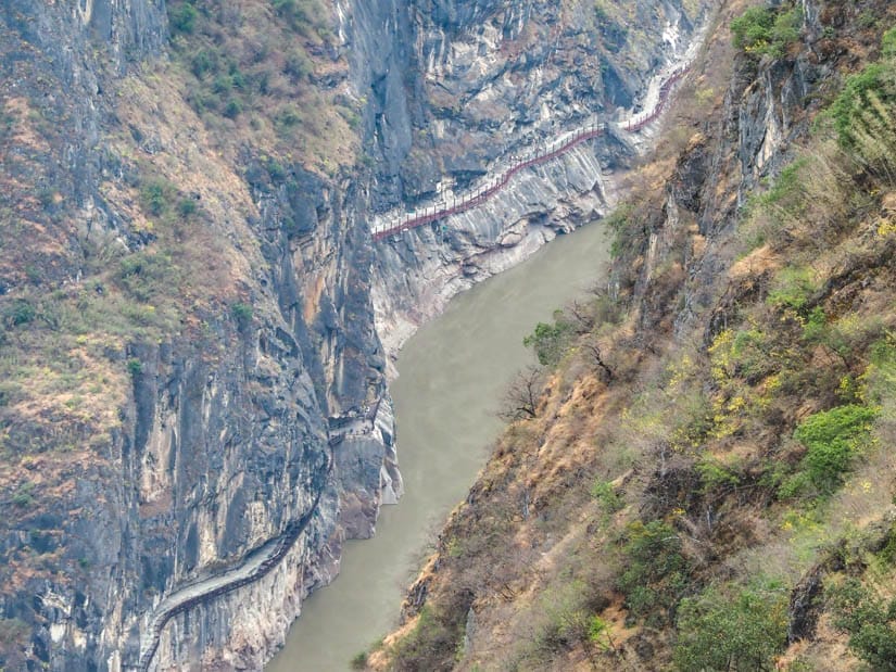 Looking down on a super narrow section of Tiger Leaping Gorge with a walking trail carved into the cliffs on the other side