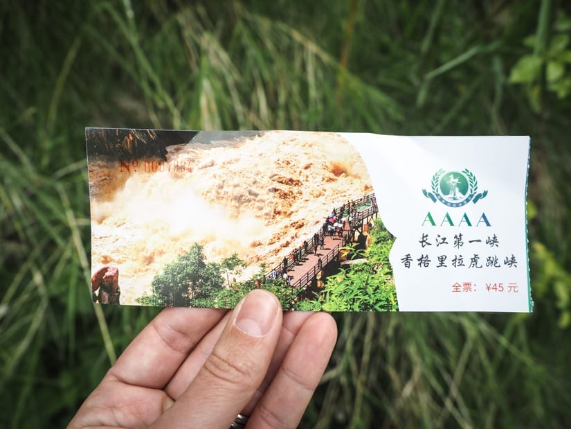 A hand holding up a ticket to Tiger Leaping Gorge