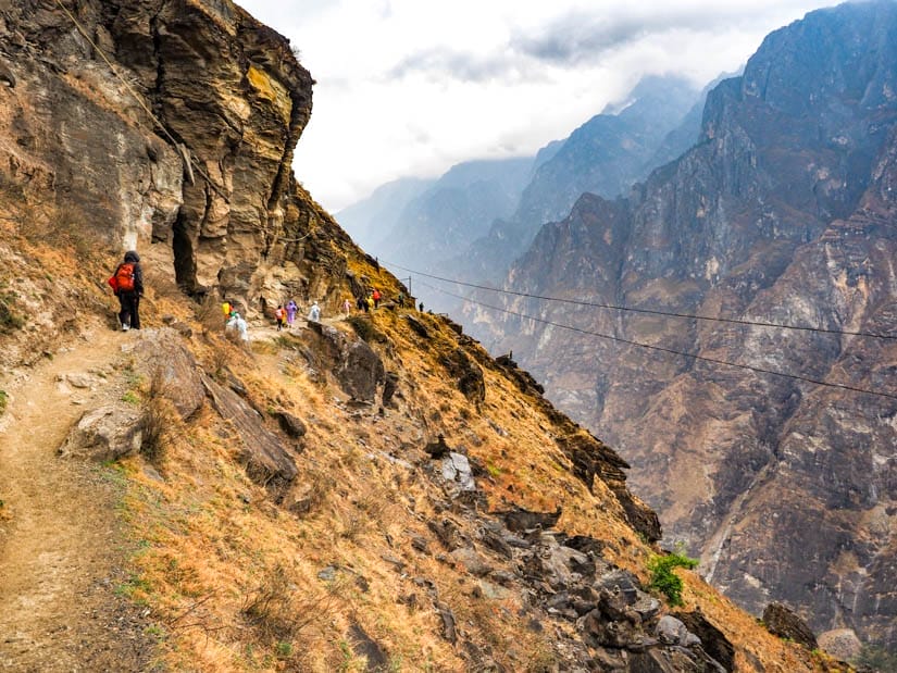 A steep hillside in Tiger Leaping Gorge with some people trekking across it